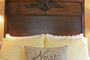 Beautifully carved German Antique Headboard with yellow bedding and nest pillow